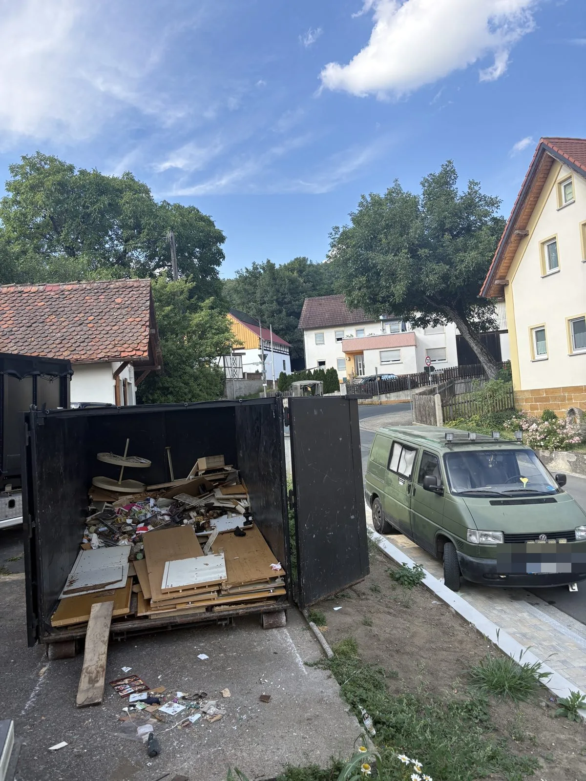 Müllmulde im Einsatz Volle Müllmulde bei einer Entrümpelung – Sperrmüll fachgerecht verladen